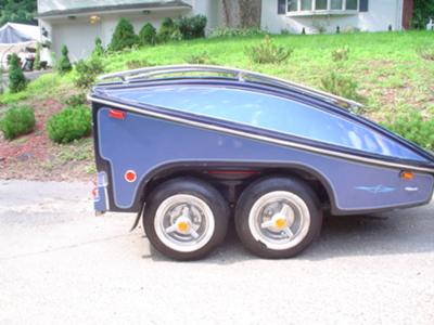 THE DUAL AXLE TRAILER HAS A CUSTOM FITTED COVER
